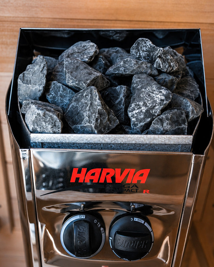 The Harvia Vega Compact heater in the Forge Indoor, loaded with sauna stones, with its thermostat and timer dials