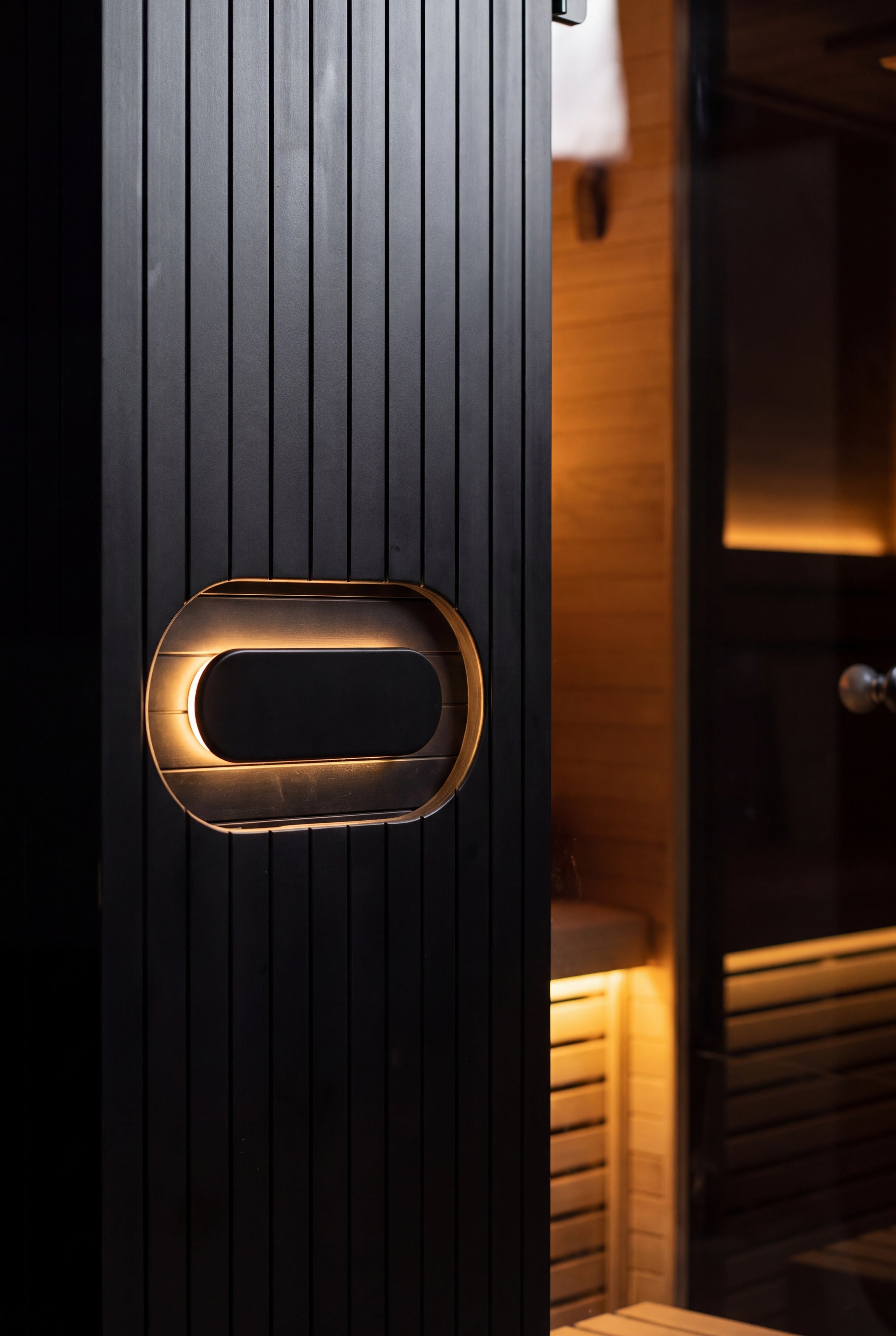The oval handle of the Forge Indoor, glowing warm against the black Hemlock